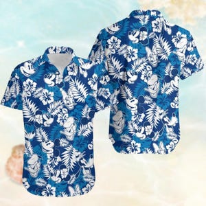 Könnte beinhalten: Ein blaues und weißes kurzärmeliges Hemd mit Knöpfen und einem tropischen Druck mit Mickey Mouse, Donald Duck und Hibiskusblüten.