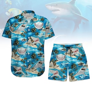 May include: A blue and white patterned shirt and matching shorts featuring a tropical beach scene with palm trees and sharks.