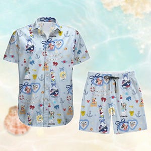 May include: A blue and white patterned button-up shirt and matching shorts. The shirt and shorts feature a nautical theme with anchors, bows, and a ship. The pattern also includes Mickey Mouse and Minnie Mouse characters.