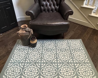 May include: A tufted brown leather armchair with a high back and rolled arms. A gray rug with a white floral pattern is on the floor. Decorative pottery is on the rug. The scene is set in a home interior.