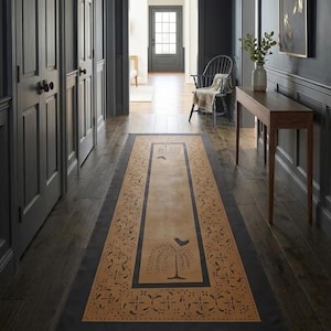 May include: A long rectangular runner rug featuring a tan center panel with a dark gray border. The rug displays a repeating floral pattern along the edges and a central graphic of a stylized bird perched on a tree branch in dark gray ink.
