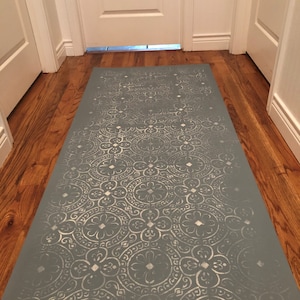 May include: A gray and white patterned rug with a geometric design. The rug is laid out on a hardwood floor in a hallway.