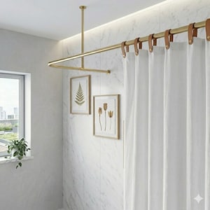 May include: A gold-coloured, U-shaped shower curtain rail is suspended from the ceiling. White shower curtains hang from the rail, attached with brown leather straps. Two framed botanical prints hang on the marble wall.