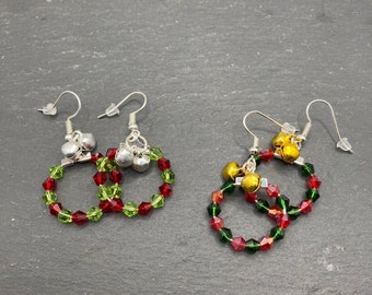 May include: Two pairs of hoop earrings featuring faceted red and green crystal beads arranged in a circular pattern. One pair includes silver-toned jingle bells, while the other pair features gold-toned jingle bells, both attached to silver-toned earring hooks.