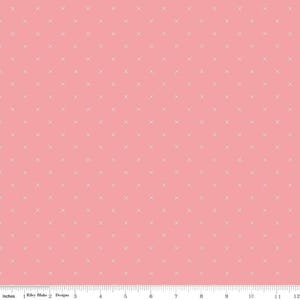 May include: A pink fabric with a repeating pattern of small, light-colored crosses. The fabric is a solid color with a grid of evenly spaced crosses. The image includes a ruler along the bottom edge, with measurements in inches.