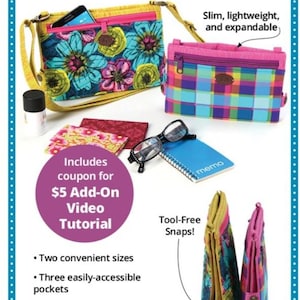 May include: Foldilocks easy foldup wallet byannie.com. Two rectangular wallets, one with a blue floral pattern and yellow strap, the other with a multicolored plaid pattern. Accessories include glasses, a memo pad, and a small bottle.