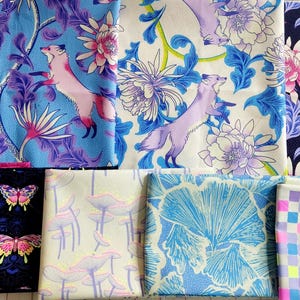 May include: A collection of patterned fabric swatches. Designs include floral patterns, foxes, butterflies, and geometric shapes in various colors such as blue, pink, purple, and white. The fabrics are likely for crafting or sewing projects.