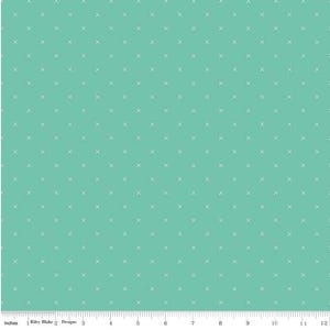 May include: A teal fabric with a repeating pattern of small white crosses. The fabric is measured in inches along the bottom edge, with a ruler showing up to 12 inches.