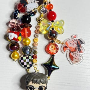 May include: A beaded keychain featuring Harry Potter and Dobby charms, along with various colorful beads and a gold-toned clasp. The keychain includes a small Harry Potter figurine, a Dobby charm, and a charm with the word "GRYFFINDOR".