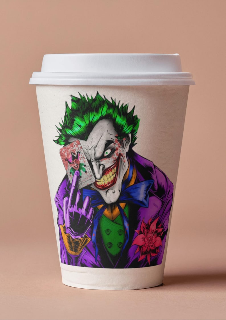 May include: A white paper coffee cup featuring a colorful illustration of the Joker from DC Comics. The Joker is depicted with green hair, white face paint, and a purple suit, holding a playing card. The design is a vibrant and detailed graphic.