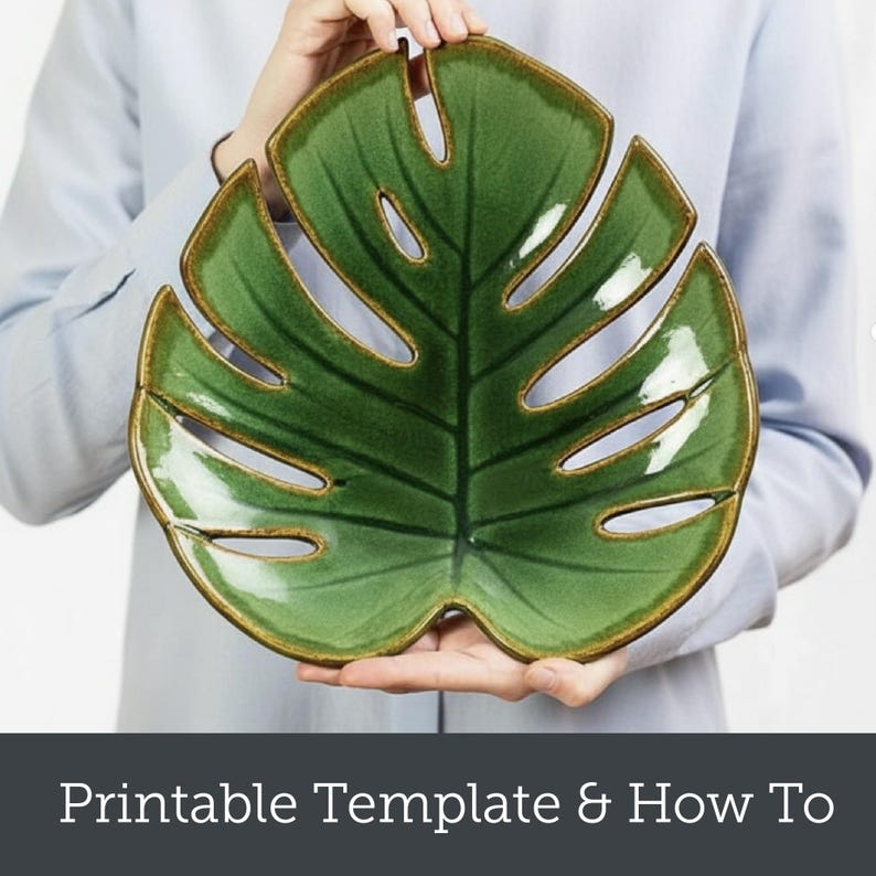 May include: A green ceramic leaf-shaped serving dish with a brown rim. The dish has a glossy finish and is held by a person wearing a light blue shirt. The dish is designed to resemble a monstera leaf.
