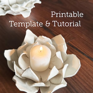 Può includere: Un portacandele bianco a forma di petalo con una candela bianca accesa al centro. Il testo "Printable Template & Tutorial" è visualizzato in bianco. Il portacandele è su una superficie di legno.