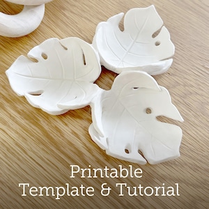 May include: Three white, leaf-shaped dishes with a monstera leaf design are arranged on a wooden surface. The dishes have a textured appearance and are slightly concave. The image also includes the text "Printable Template & Tutorial".