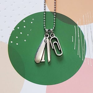 May include: A silver necklace with a silver paperclip and a silver stapler charm.
