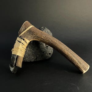 May include: A white ceramic mug with a black handle and the text "But First, Coffee" in a black, handwritten-style font. The mug is on a white surface.