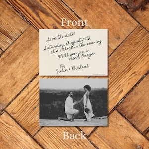May include: Wedding invitation card with a black and white photo of a couple. The front of the card has handwritten text: "Save the date! Saturday, August 26th at 5 o'clock in the evening. We'll see you in Bend, Oregon. Xo, Julie & Micheal."