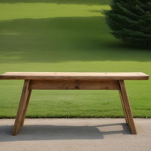 May include: A rustic wooden table with a natural finish and a simple design. The table has a rectangular top and two angled legs on each side. The table is sitting on a concrete surface.