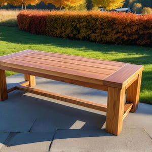 Puede incluir: Una mesa de madera larga y rectangular con un acabado de madera natural. La mesa tiene un diseño simple y moderno con líneas rectas y un borde ligeramente elevado. La mesa está hecha de madera maciza y tiene una superficie lisa y pulida.