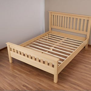 May include: A natural wood bed frame with a slatted headboard and footboard. The frame is made of solid wood and has a simple, classic design.