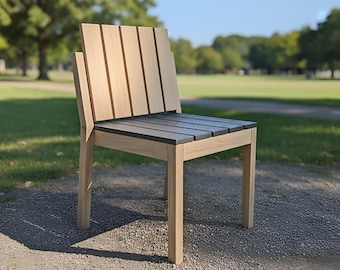Könnte beinhalten: Ein Holzstuhl für den Außenbereich mit Lattenrücken und -sitz. Der Stuhl ist aus hellem Holz mit einem dunkelgrauen Sitz gefertigt. Der Stuhl steht auf einem Schotterweg mit einem grasbewachsenen Park im Hintergrund.