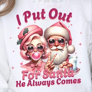 May include: White sweatshirt with a pink and white illustration of a woman with a pink bubble and Santa Claus. The text reads "I Put Out For Santa He Always Comes".
