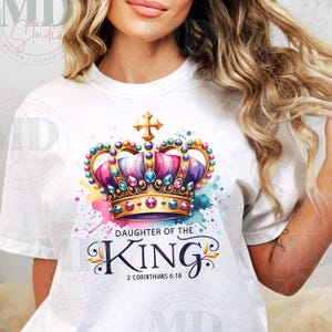 May include: White t-shirt with a colorful crown design and the text "Daughter of the King" with the scripture reference "2 Corinthians 6:18".
