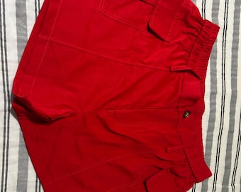 Schattige rode shorts met zakken aan beide zijkanten en een bruine knoop. Geen zakken aan de achterkant, eerder een hoog model, afhankelijk van je figuur.