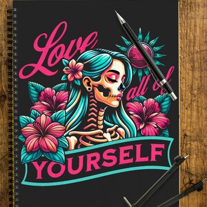 Könnte beinhalten: Schwarzes Spiralnotizbuch mit einer farbenfrohen Illustration. Das Kunstwerk zeigt eine Frau mit Skelettgesicht, türkisfarbenem Haar und rosa Blumen. Der Text lautet "Love Yourself" in Pink und Türkis.