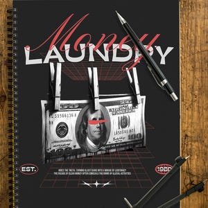 Könnte beinhalten: Schwarzes Spiralnotizbuch mit dem Wort "Money Laundry" in Rot und Weiß. Das Design zeigt ein Raster, Dollarnoten und Wäscheklammern. Ein Stift und ein Zirkel liegen auf der Holzoberfläche.