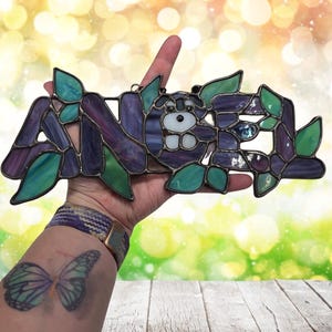 Baby name "Angel" being held to show size. A five letter name will be approximately  7" wide and 5" high.