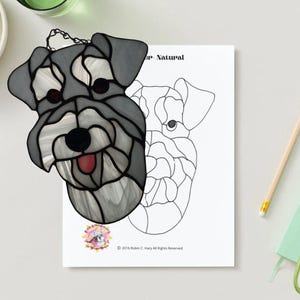 Könnte beinhalten: Ein hängendes Buntglasfenster mit einem Miniatur-Schnauzer in Schwarz-Grau. Der Hund hat eine rosa Zunge herausgestreckt. Das Bild enthält eine schwarz-weiße Umrandung des Hundes zum Ausmalen.