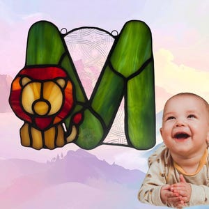 Alphabet letter- M- with Lion. Lion is made with amber glass while M is made with green. Background glass is clear with Celtic design. Lion represents March.