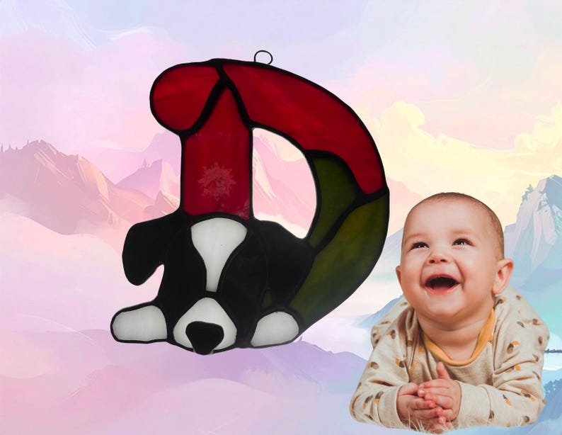 Alphabet letter-D- shown with a puppy. Letter is made of red and green glass while the puppy is made of black and white glass. Puppy represents December.