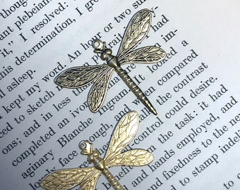 May include: Two gold-toned dragonfly charms with intricate details. The charms are on a white background with text.