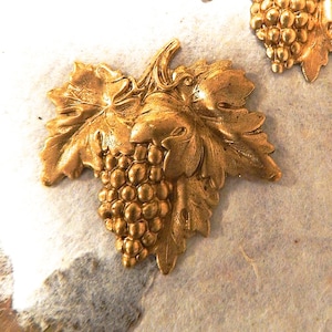 May include: A gold-colored metal grapevine design with leaves and grapes. The design is detailed and intricate.