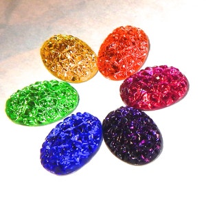 May include: Six oval-shaped, iridescent glass cabochons in a rainbow of colors. The cabochons are arranged in a circle, with the colors transitioning from yellow to orange, red, purple, blue, and green.