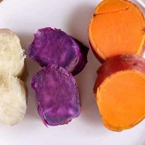 May include: A white plate holds several pieces of cooked sweet potatoes. The sweet potatoes are cut open, revealing the orange, purple, and white flesh. The sweet potatoes are a healthy food.