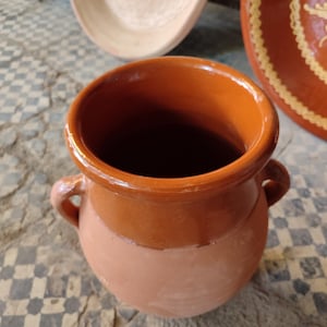 Our Moroccan tanjia is meticulously crafted from high-quality ceramic, designed specifically for the slow-cooking methods of Marrakech cuisine. This terracotta dish features the characteristic narrow opening that helps intensify flavors during the long cooking process. The unglazed interior develops a natural patina over time, enhancing your tanjia dishes with each use. Perfect for preparing traditional Moroccan lamb or beef recipes with aromatic spices.