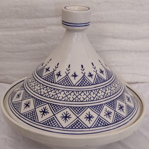 This exquisite moroccan ceramic tagine is a culinary and artistic masterpiece. Featuring a vivid blue ceramic tagine lid and intricate traditional Islamic patterns, it is both functional and decorative. Use it as a berber tagine for your favorite dishes or as a centerpiece authentic Moroccan serving dish. Handmade with care, it represents the best of handmade pottery and traditional tagine design.
