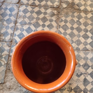 Our ceramic tanjia is handcrafted by skilled Moroccan artisans using time honored techniques. This terracotta dish features the distinctive urn shape essential for proper tanjia preparation, with a narrow neck that locks in moisture and flavor. The natural ceramic construction ensures even heat distribution for perfect slow cooked results every time. Excellent for preparing authentic Moroccan dishes or as a unique serving vessel.