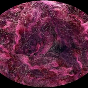 May include: A close-up of a bundle of pink and purple wool fibers. The fibers are soft and fluffy, and they are perfect for knitting or crocheting.