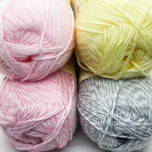 May include: Four balls of yarn in pastel colors. Two pink balls of yarn, one solid and one with white strands. A yellow ball of yarn and a gray ball of yarn with white strands are also visible.