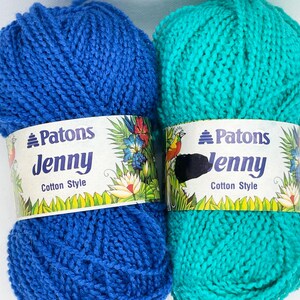 May include: Two skeins of Patons Jenny Cotton Style yarn in vibrant colors. One is a bright blue, the other a teal green. Each skein has a decorative label with the brand name, yarn type, and floral and bird illustrations.
