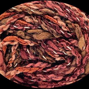 May include: A skein of yarn in shades of brown, pink, and red. The yarn is made of a blend of silk and cotton.