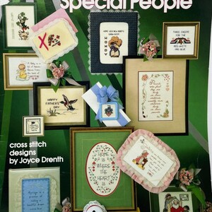May include: A collection of framed cross-stitch designs with various themes, including holiday, family, and inspirational quotes. The designs feature floral and character motifs, with text such as "Happy Father's Day" and "Home is Where the Heart Is."