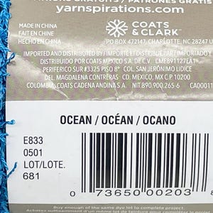 Pode incluir: Uma etiqueta de fio azul, com a palavra "OCEAN" e um c&oacute;digo de barras. A etiqueta tamb&eacute;m inclui a marca "COATS & CLARK" e o site "yarnspirations.com".