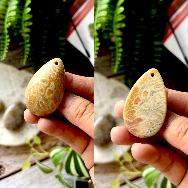May include: A teardrop-shaped pendant with a hole at the top. The pendant is a light tan colour with darker brown and beige patterns. The stone has a polished finish and is held in a hand.