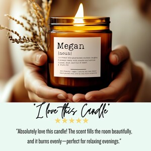 May include: A brown glass candle with a white label that reads "Megan [noun] 1. A friend who guarantees endless laughs 2. Always ready with snacks and advice 3. Loyal, kind, and full of heart 4. Pure Joy eco-friendly | vegan | natural soy wax blend hand poured with love by cozy kind collective".