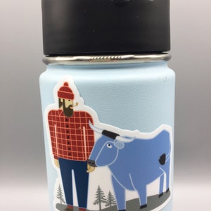 May include: A blue stainless steel water bottle with a black lid. A sticker of a cartoon lumberjack with a red and black checked shirt and a blue ox is on the bottle.