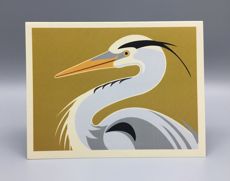 May include: A stylised illustration of a grey heron with a black head and a long, orange beak against a gold background.
